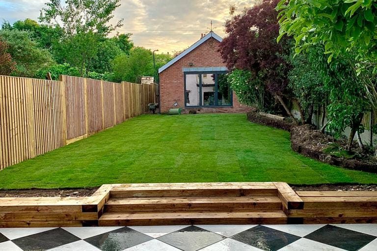 New grass lawn with railway sleeper steps and paving